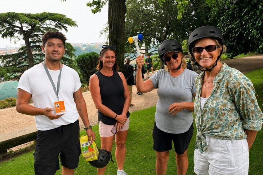 Four people outdoors, one holding a hammer, another with a helmet, and two with bags. 3