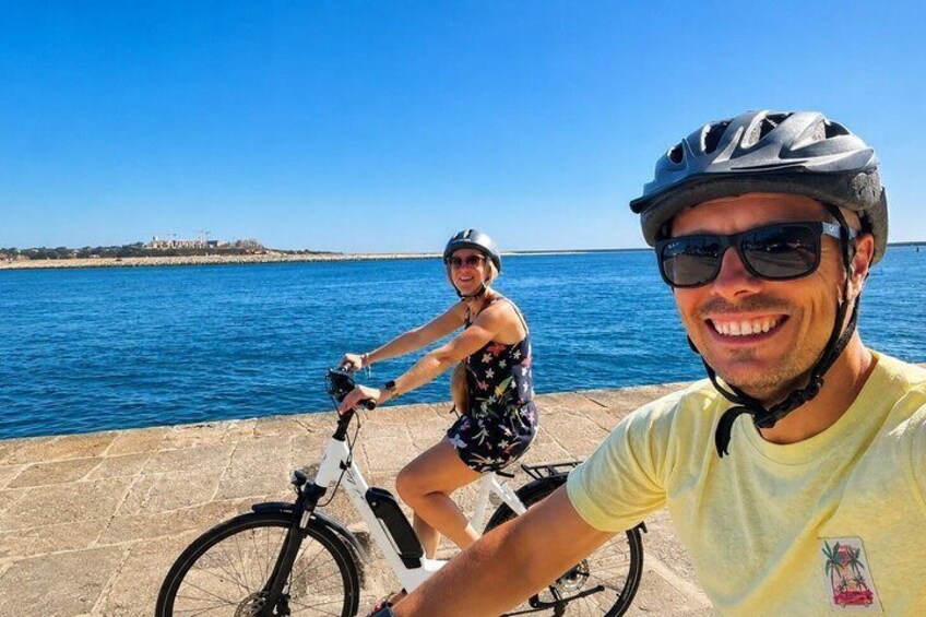 Two people on bicycles by a waterfront with a clear sky. 1