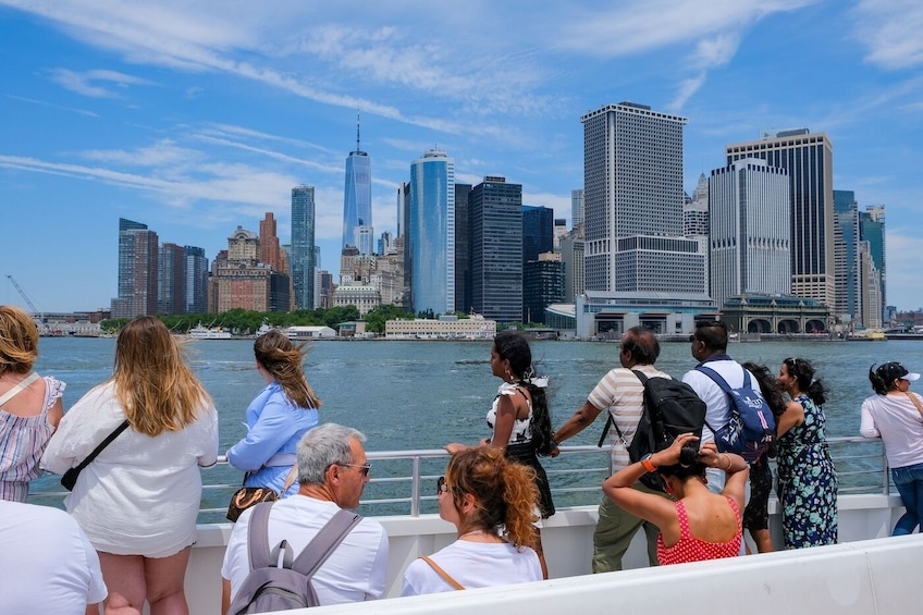 A group of people on a boat, overlooking a city skyline with modern skyscrapers. 3