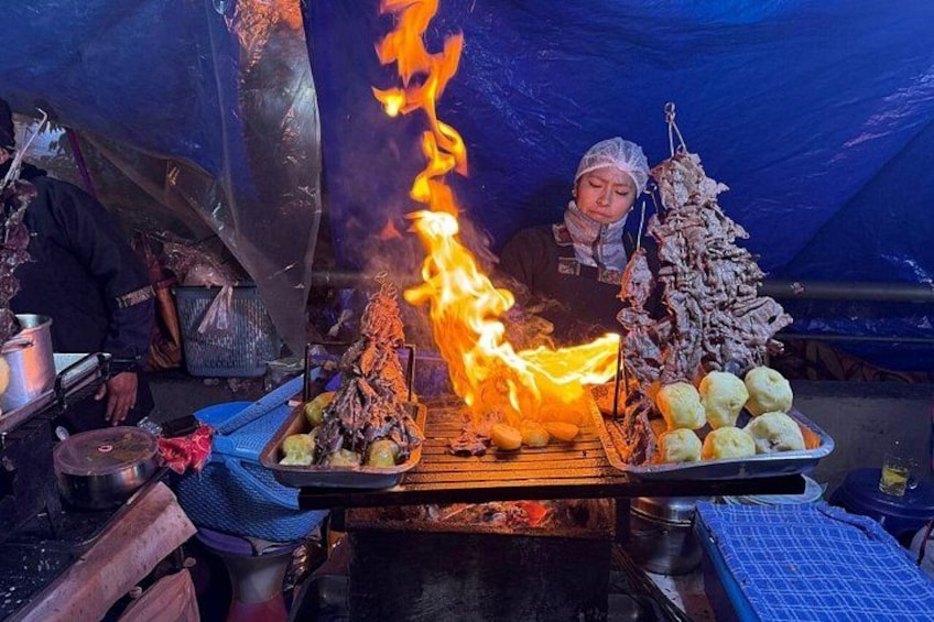 A person cooking food over an open flame in a tent. 1