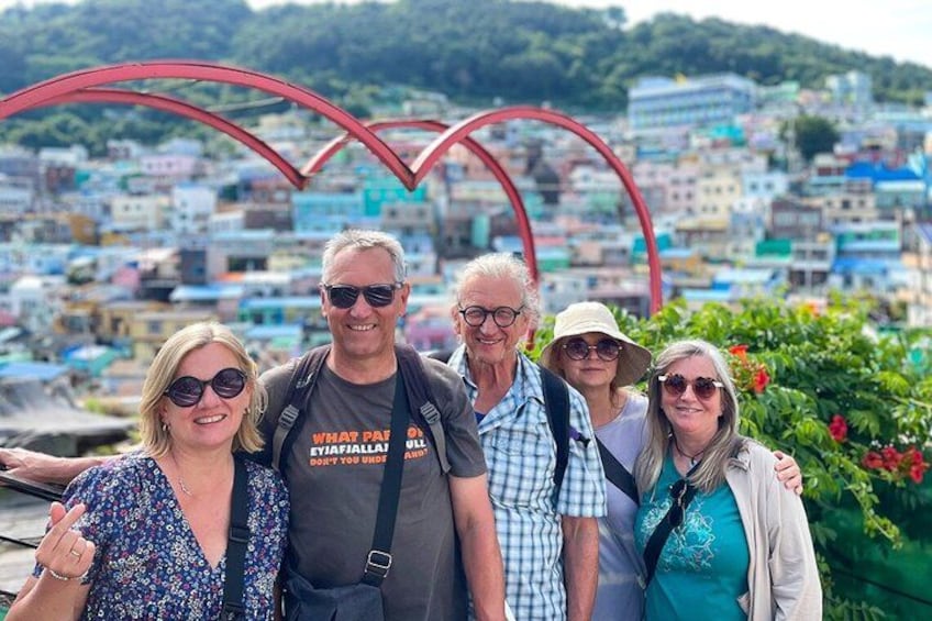 A group of people standing in front of a red arch structure with a cityscape in the background. 4