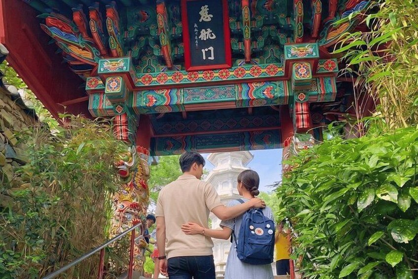A traditional Chinese gate with intricate designs and a couple standing beneath it. 2