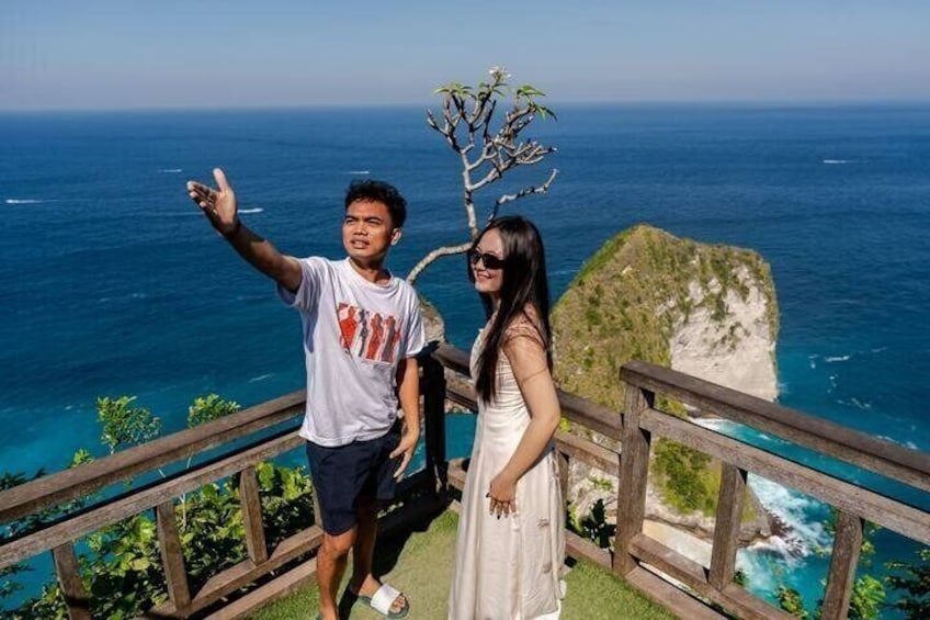 A man and a woman standing on a wooden staircase overlooking a coastal cliff with the ocean in the background. 4