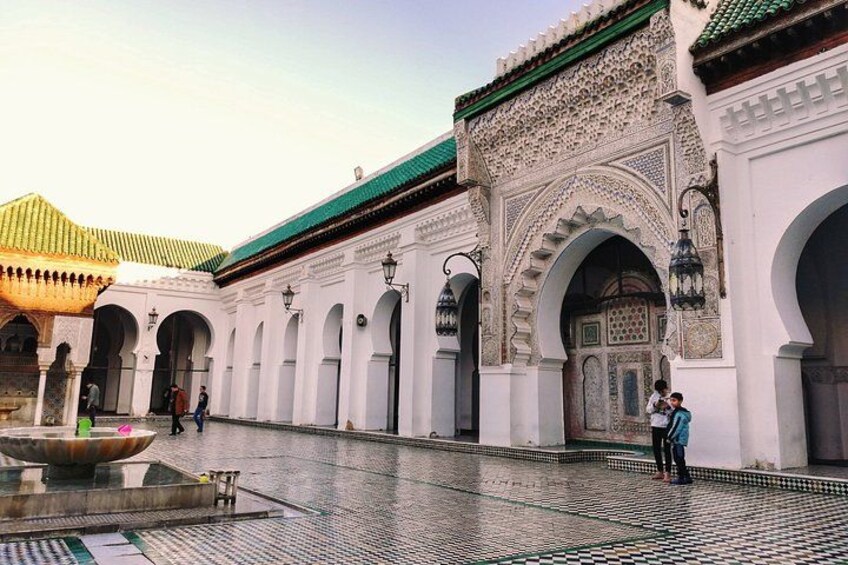 A courtyard with arches, a fountain, and a building with intricate tile work. 1