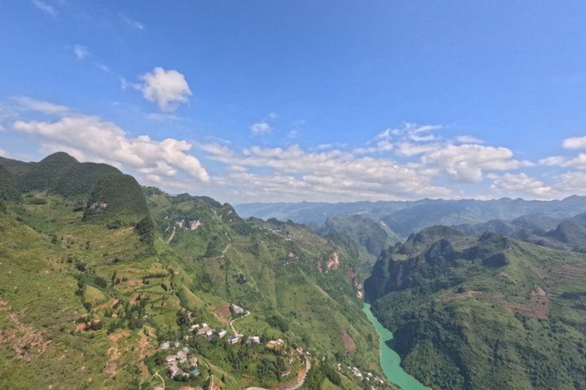 A mountainous landscape with a river, green valleys, and scattered houses. 2