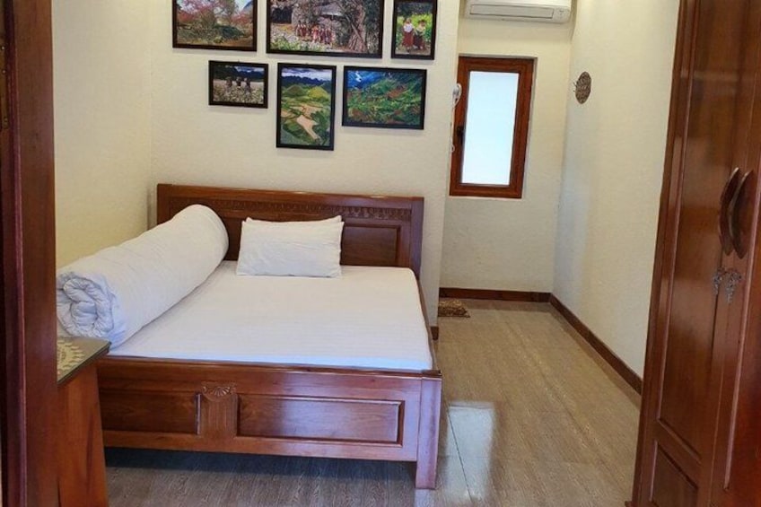A bedroom with a wooden bed, white bedding, and several framed pictures on the wall. 5