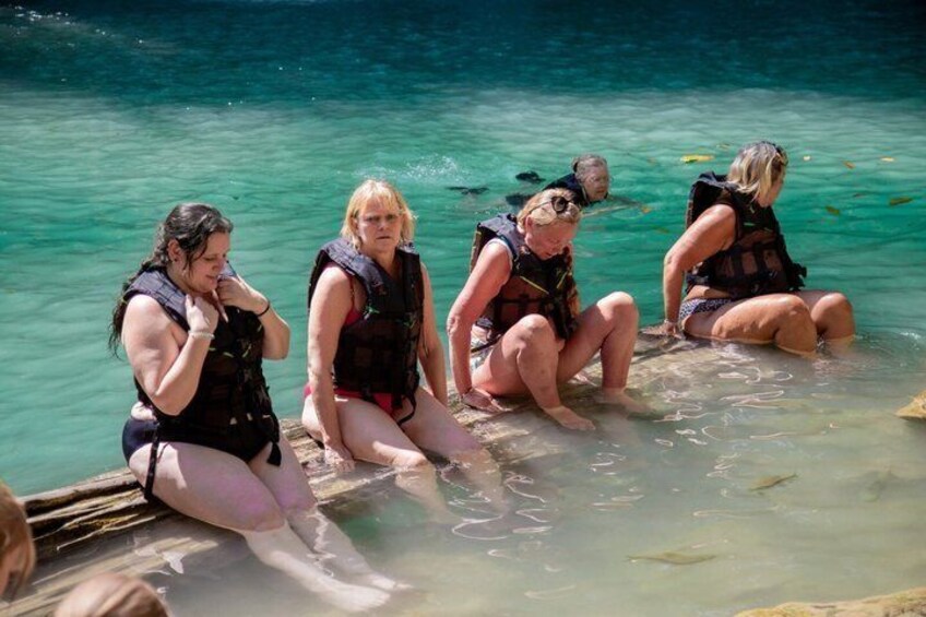 People sitting on a wooden dock in clear water. 1