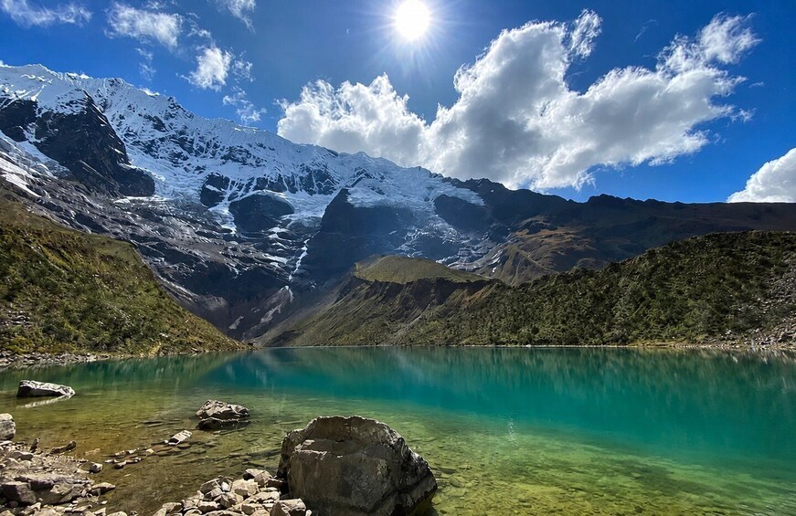 A mountain lake with clear turquoise water, surrounded by snow-capped peaks and rocky shores. 1