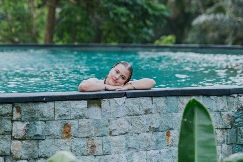 A person leaning on a stone wall by a pool with water. 3