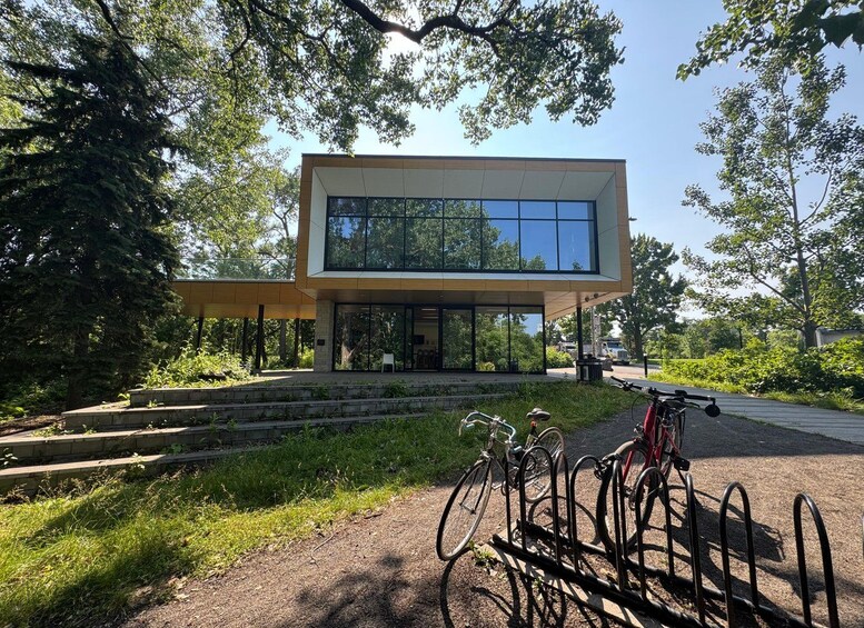 A modern building with large windows, surrounded by trees and a bike rack with bicycles. 2