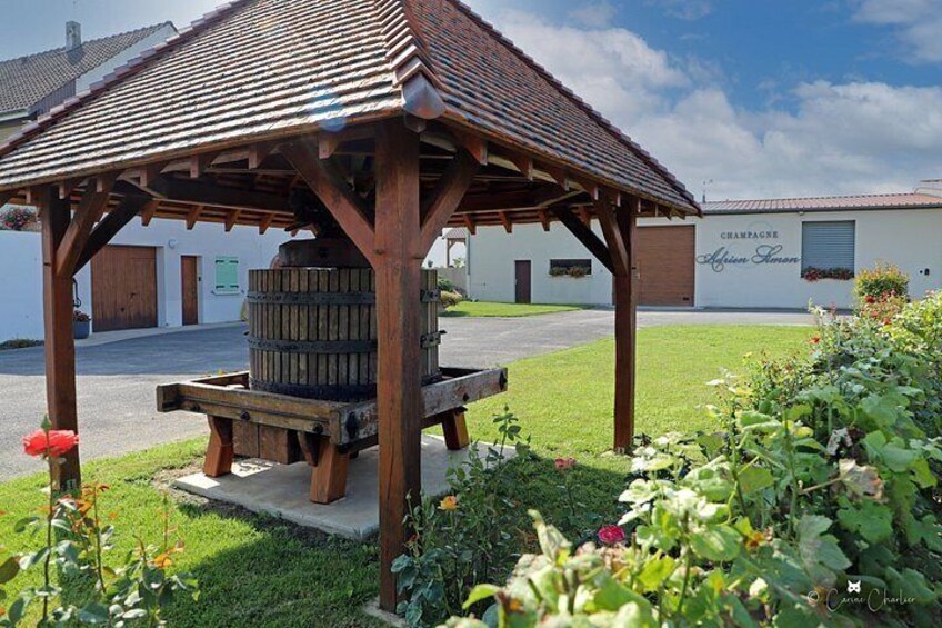 A wooden gazebo with a barrel, surrounded by a garden with flowers and a building labeled 'CHAMPAGNE.' 4