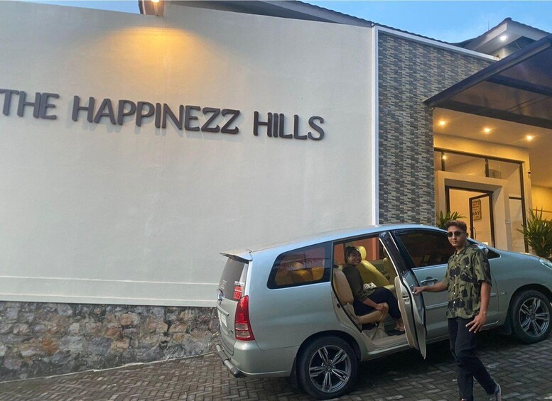 A silver minivan parked in front of a building with a sign that reads "THE HAPPINEZZ HILLS". 3