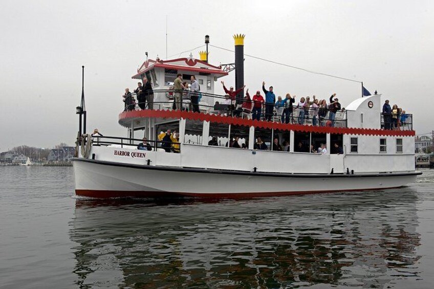 A white and red boat named 'Harbor Queen' with people on deck, docked at a harbor. 1