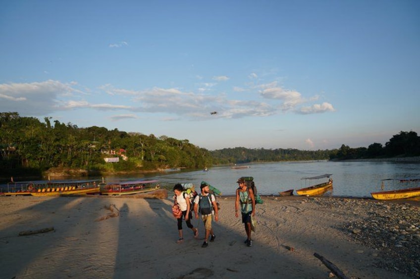 A riverbank with people walking, boats, and a bridge. 4