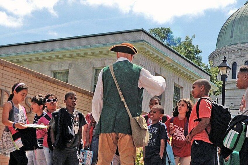 A historical reenactment scene with a person in period costume and a crowd of onlookers. 4