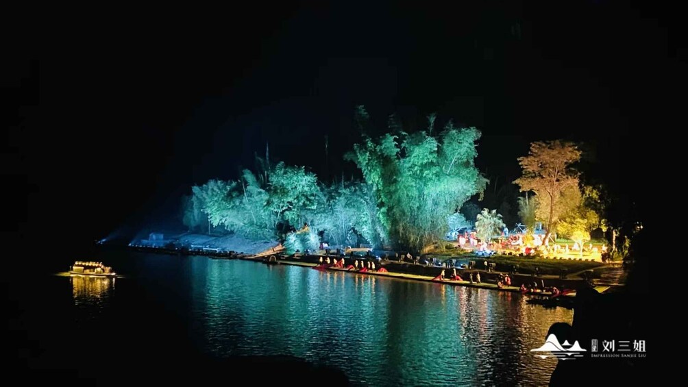 A nighttime riverside scene with illuminated trees and a dock. 1