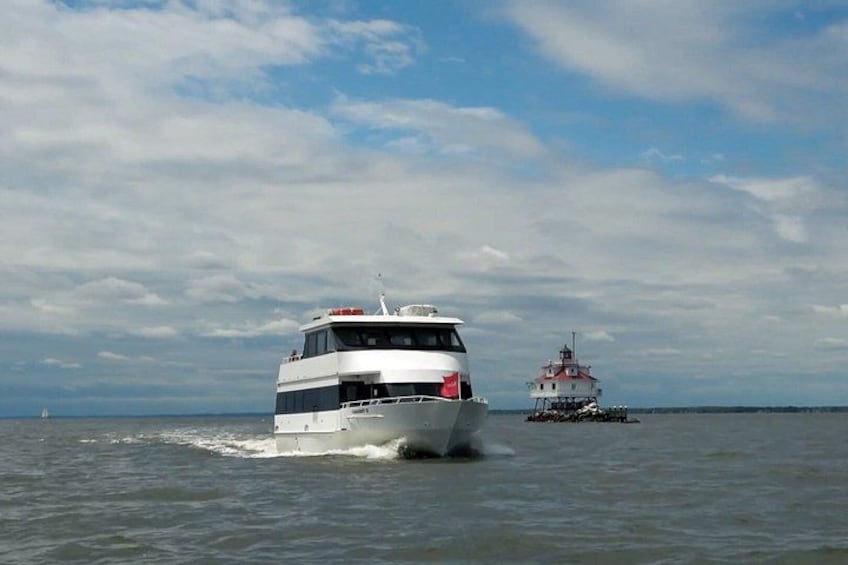 A white and black boat moving on the water with a lighthouse in the background. 2