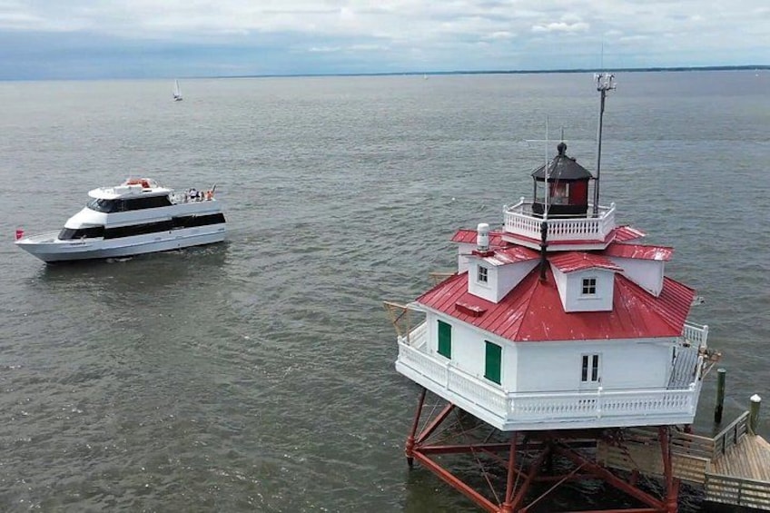 A white yacht and a red and white lighthouse on a calm body of water. 1