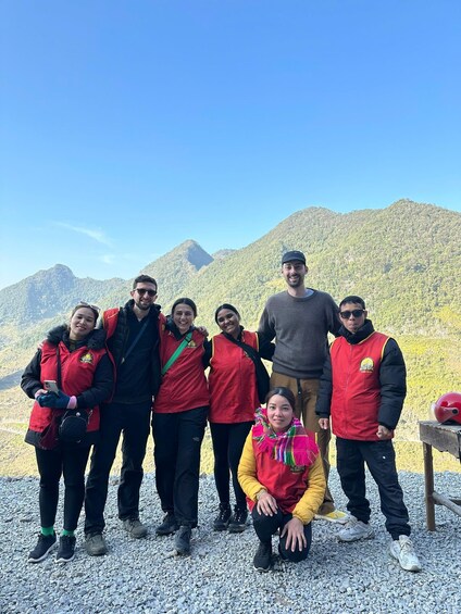 A group of people standing on a rocky terrain with mountains in the background. 5