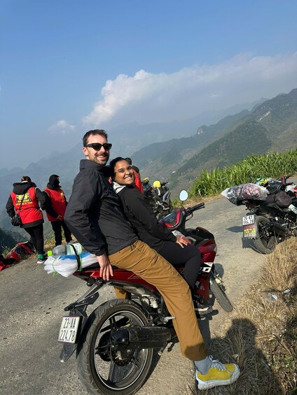 A person riding a motorcycle on a mountain road with another person sitting behind. 4