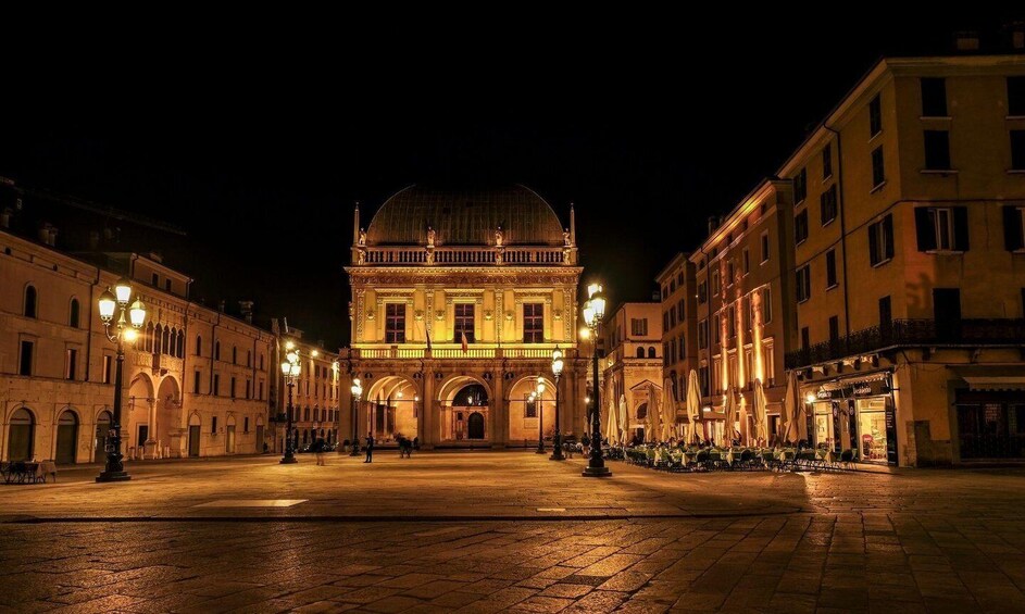 A nighttime view of a historic square with a prominent building featuring a dome. 5