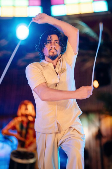 A person in a light-colored outfit performing an act with a rope. 2