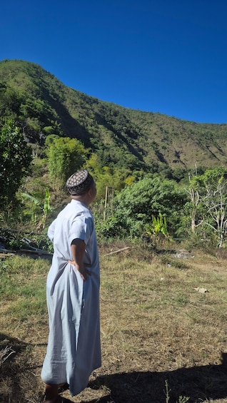A person standing in a field with a mountainous background. 4