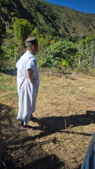 A person standing in a grassy area with a mountainous background. 3