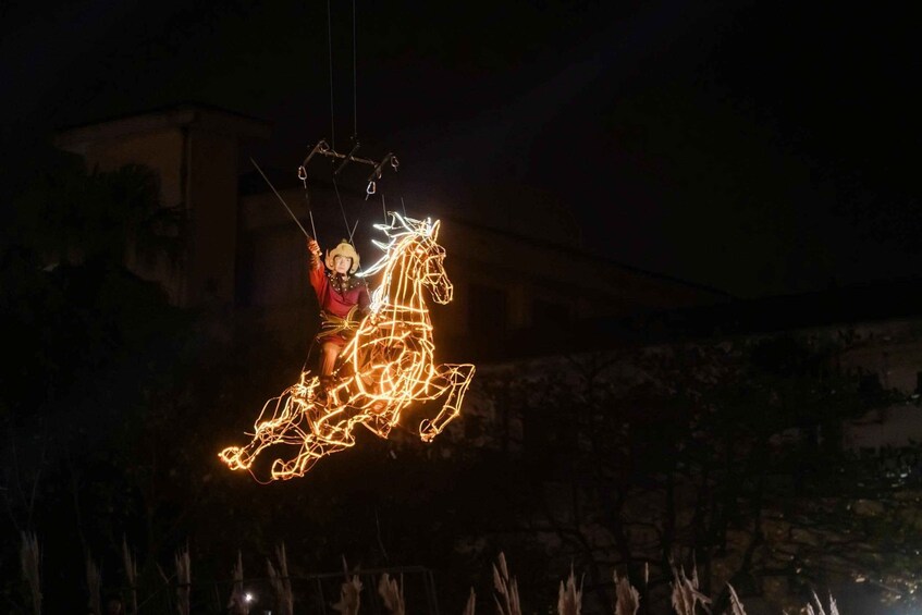 A person on a horse-shaped light installation at night. 2