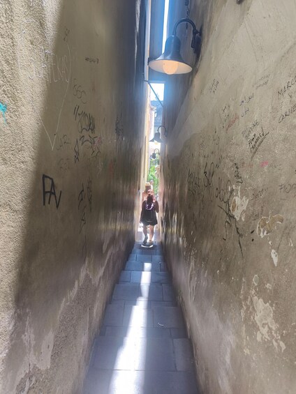 A narrow stairway with graffiti on the walls and a person descending. 2