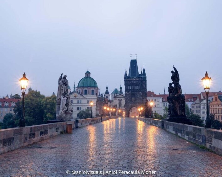 A cobblestone bridge with statues and a domed building in the background. 1