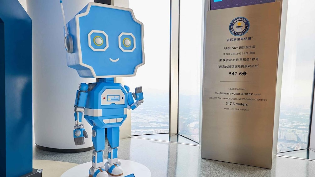 A blue robot sculpture in a modern indoor setting with a glass floor, next to a sign displaying Guinness World Records achievement. 4