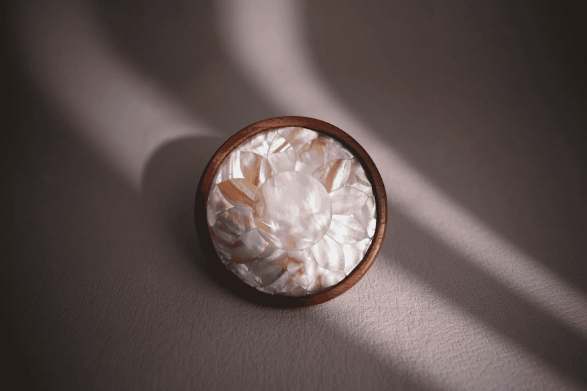 Un bol en bois rempli d’objets blancs, posé sur une surface texturée. 3