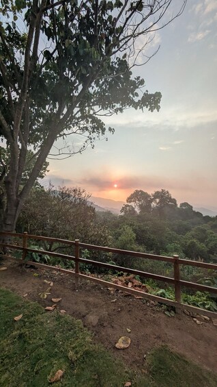 A sunset over a hilly landscape with a wooden fence in the foreground. 1