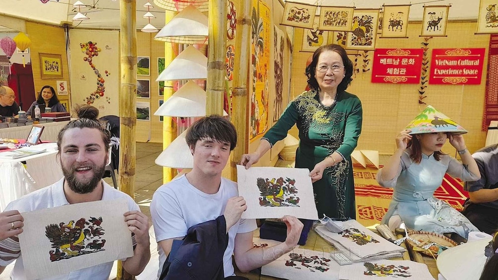 People holding up paper with a coat of arms, in a room decorated with traditional Asian art. 1