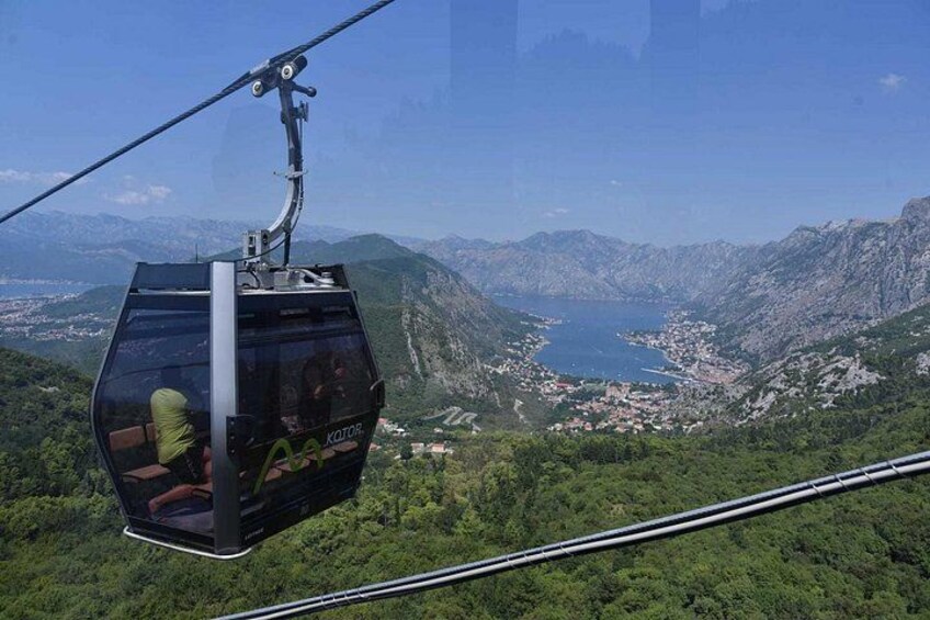 A cable car suspended over a mountainous landscape with a view of a town below. 1