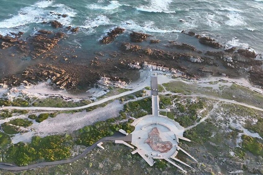 A coastal area with a circular monument surrounded by a paved walkway. 1