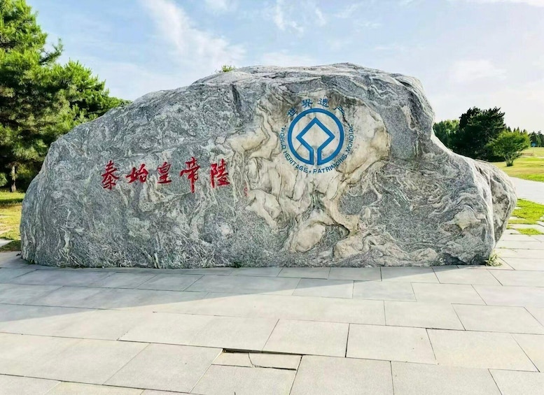 A large rock with inscriptions and a logo. 1