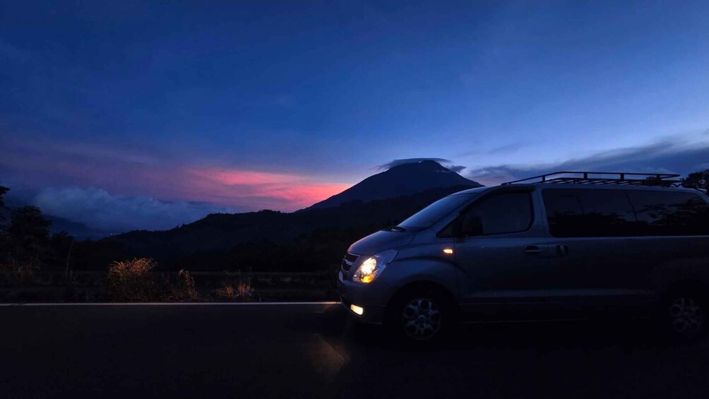 A car parked on a road with a mountain and sunset in the background. 3