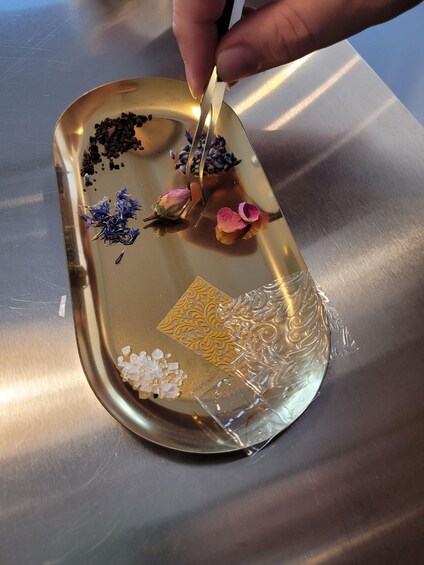 A tray with various items including dried flowers, seeds, and decorative paper. 5