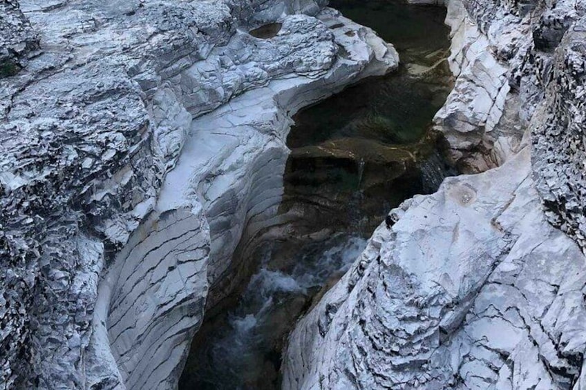 A rocky canyon with a narrow stream flowing through it. 3