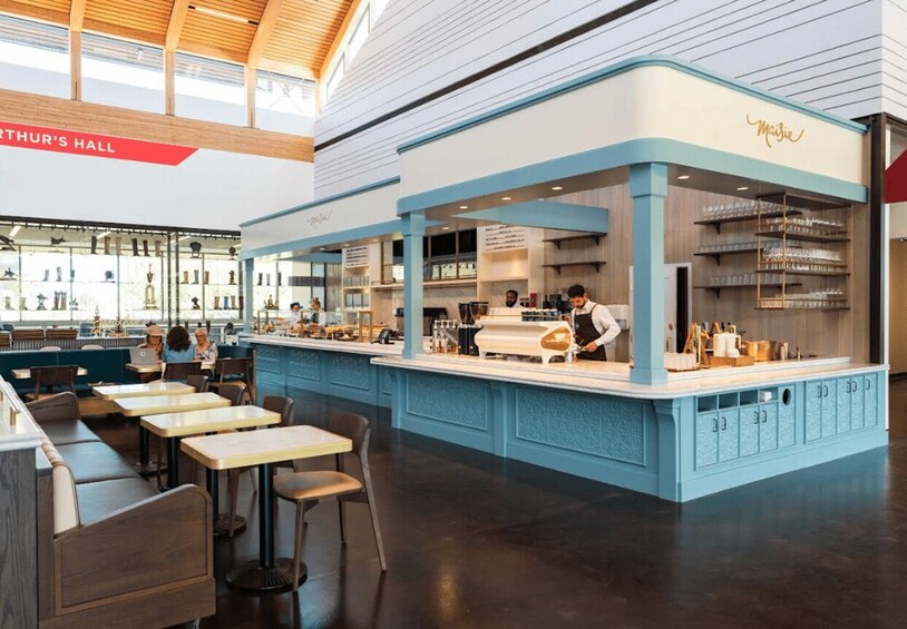 A modern cafe interior with blue accents, wooden tables, and a bar area. 2