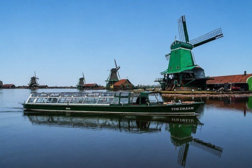 A green boat named 'The Dream' docked near traditional windmills. 1