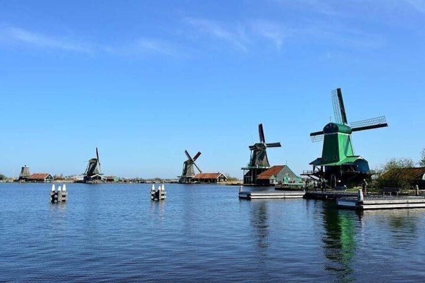 Windmills on a body of water with houses in the background. 3