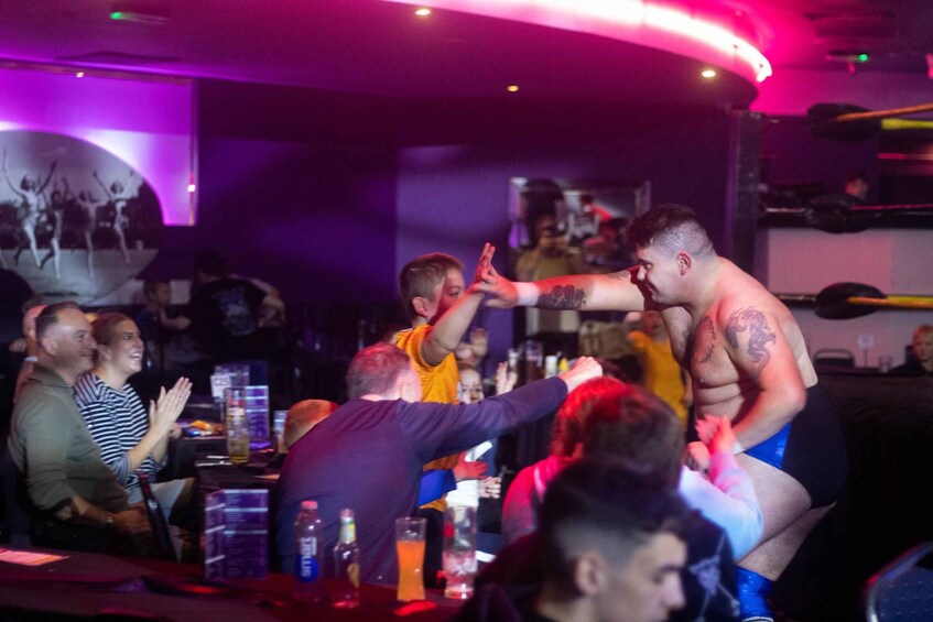 A group of people at a bar with a DJ booth in the background. 1