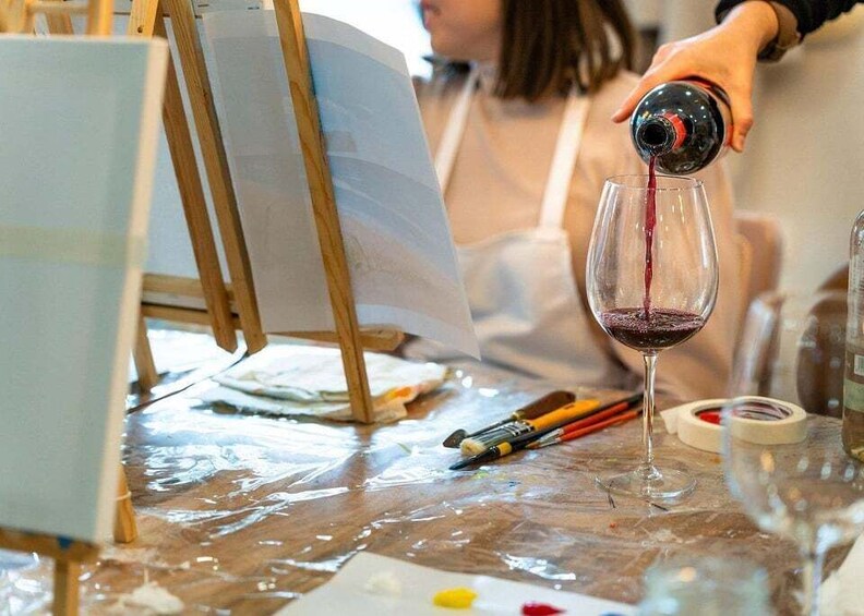 A person pouring red liquid into a glass. 4
