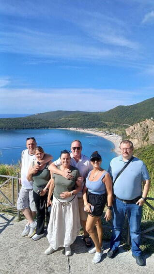 A group of people standing on a concrete path overlooking a coastal landscape with a clear blue sky. 4