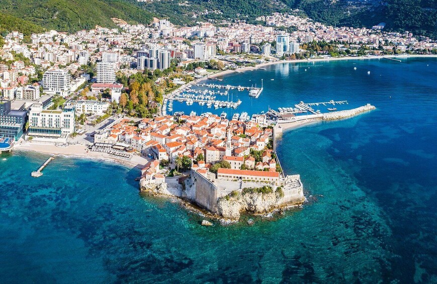 An aerial view of a coastal town with a fortified peninsula, clear blue waters, and a marina. 5