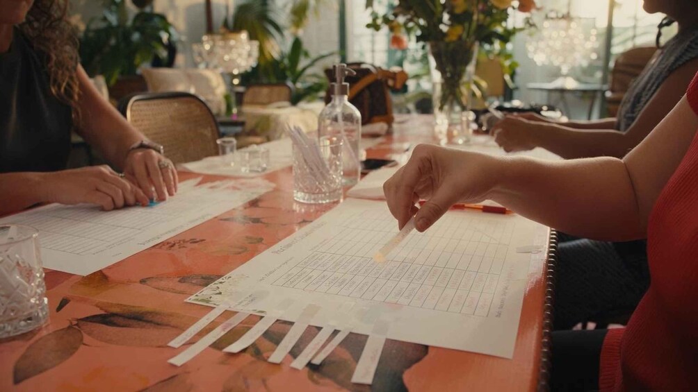 A group of people sitting at a table with papers and a pen, possibly discussing or working on something. 3
