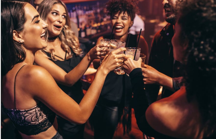 A group of people toasting with drinks in a dimly lit bar. 5